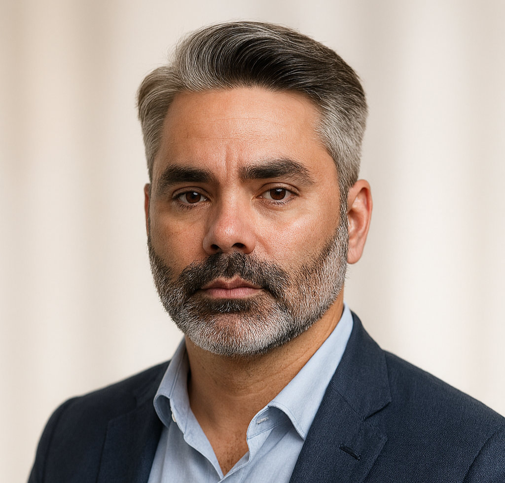 Headshot photo of Kevin wearing a blue shirt and a linen blazer.